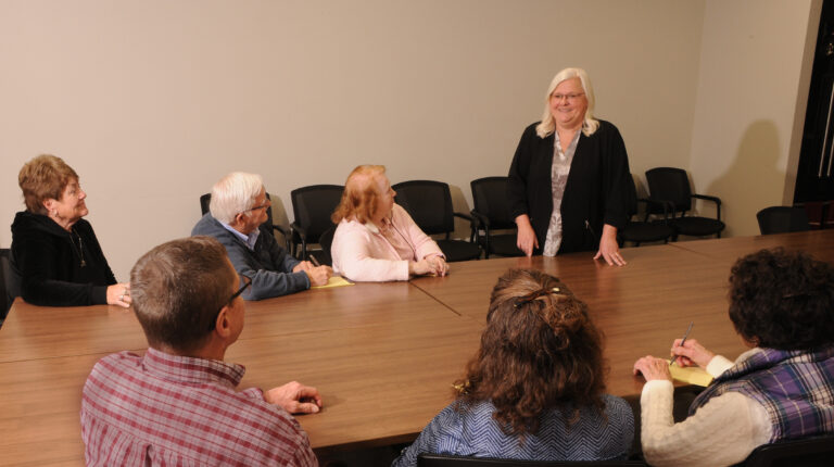 Tina standing at a table talking to a group of people